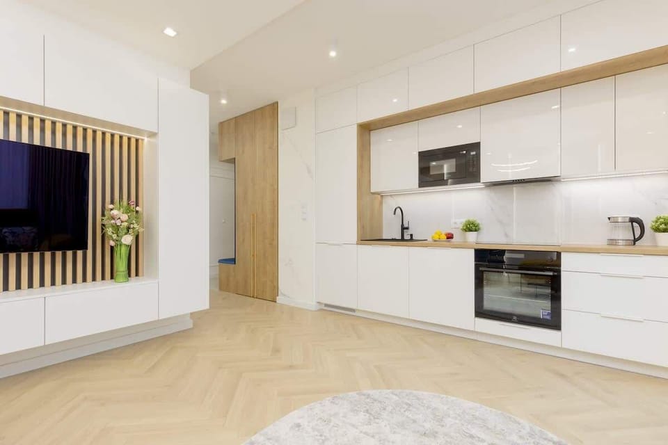 A modern kitchenette with white cabinets and a light countertop, equipped with the latest appliances and designed with a practical layout to optimize space.
