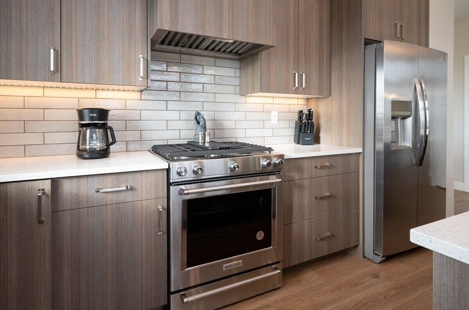 With its modern lighting, windows, quartz countertops, and stunning backsplash, the kitchen makes preparing dinner a truly enjoyable experience