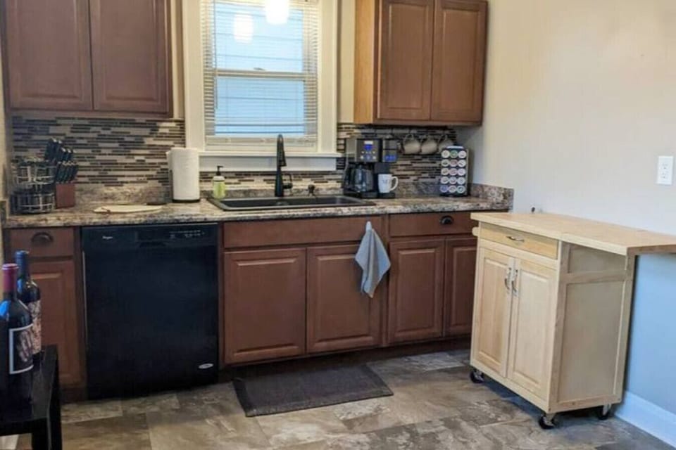 Rolling island pushed up against the wall and full view of kitchen less the appliances on the wall behind the camera