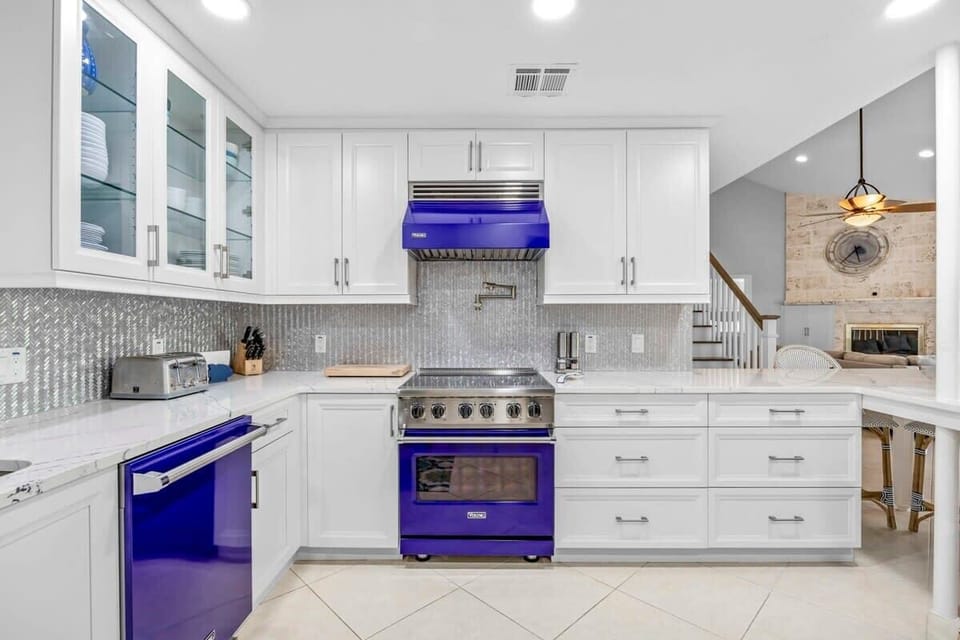 Modern kitchen featuring striking blue appliances and white cabinetry.