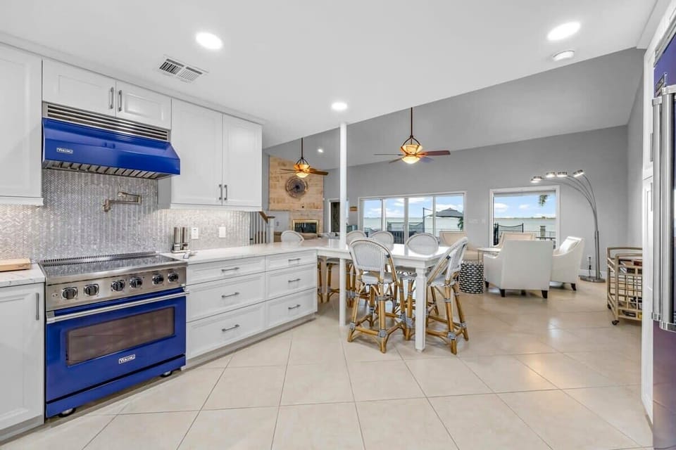 Modern kitchen with blue Viking appliances and an open dining area overlooking the living room.