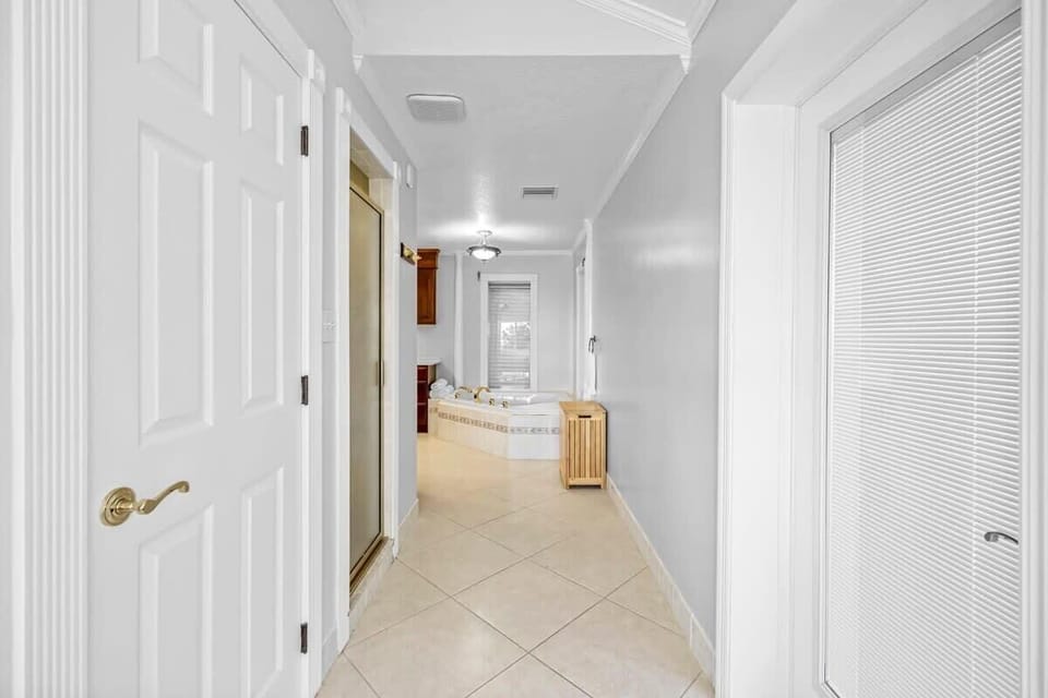 hallway leading to a bathroom with a large soaking tub and tiled floors