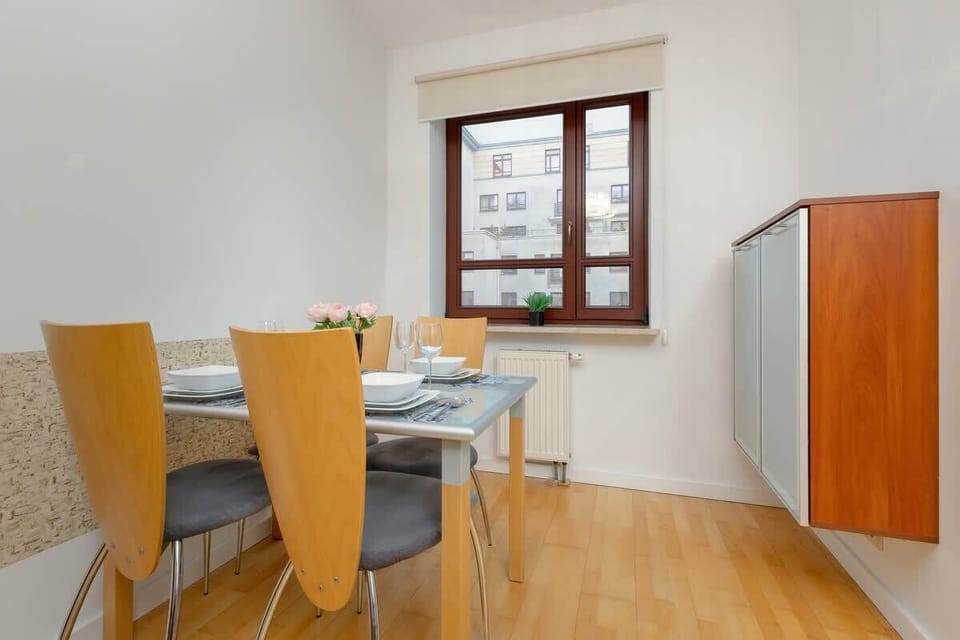 A dining area with a wooden table and chairs, well-lit by natural light.