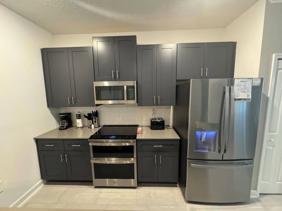 Discover a beautifully designed kitchen featuring sleek dark cabinetry and stainless steel appliances, perfect for meal prep and socializing with friends while enjoying the modern countertop setup for all your culinary needs.