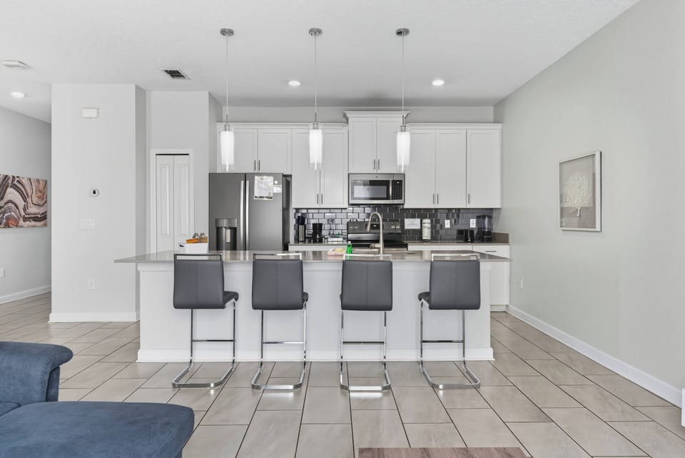 Experience a modern kitchen with polished granite countertops and stainless steel appliances, ideal for your culinary creations. The sleek white cabinetry and chic bar stools blend style and functionality seamlessly.