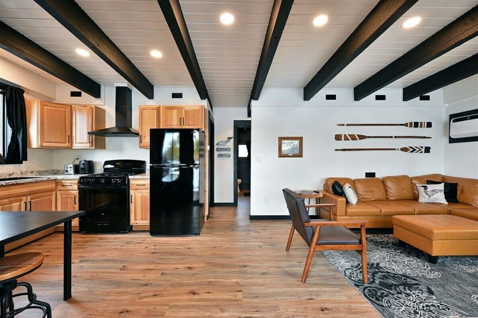 Loon's Nest has an open-concept that showcases warm wood-paneled walls, white ceilings with bold black exposed beams, and large windows that look out onto Buskey Bay.