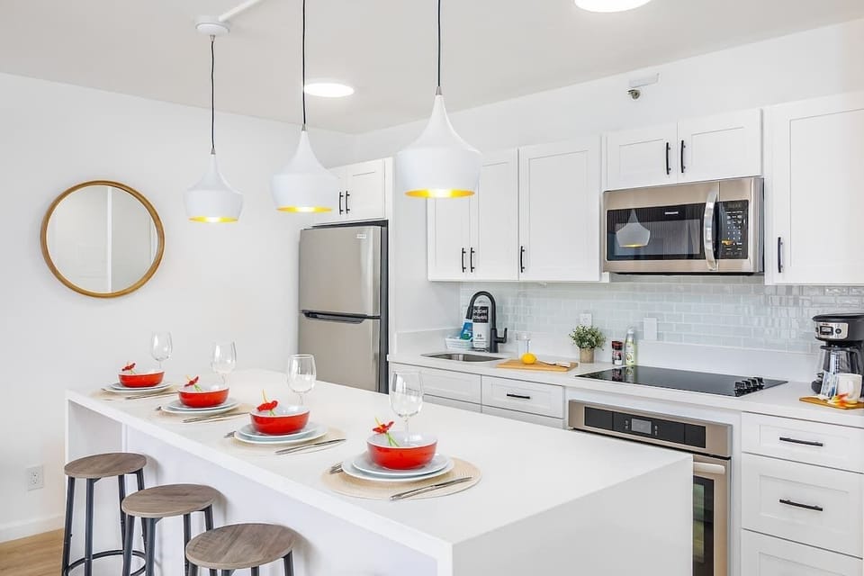 Cook in style in this fully-equipped, modern kitchen, featuring a spacious eat-in bar and sleek stainless steel appliances.