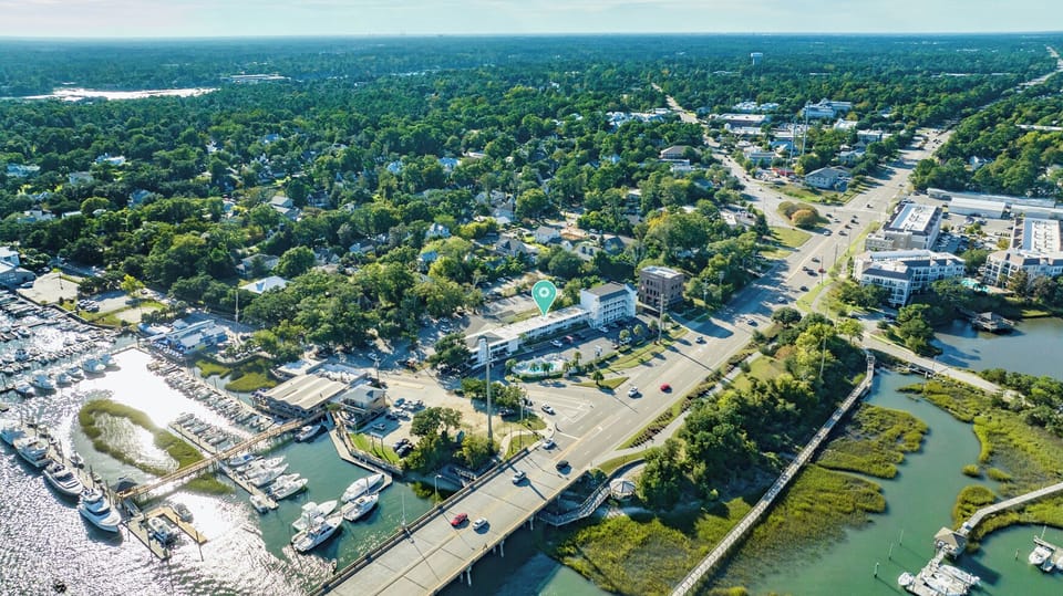 Aerial view showcasing the property's waterfront location amid lush greenery and marina access, with nearby community amenities and scenic waterways defining the surrounding area.