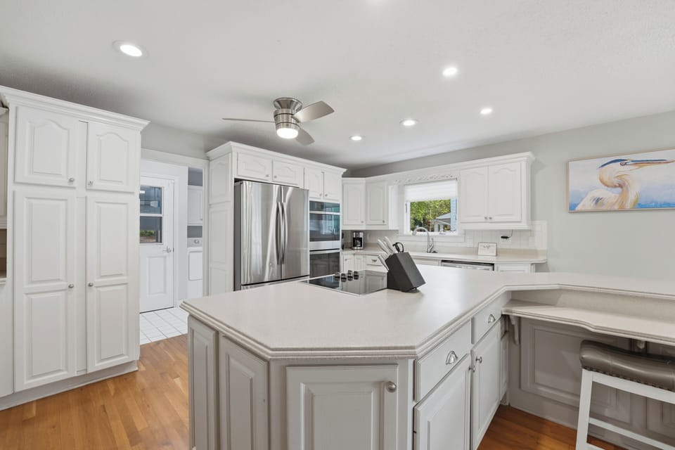 Spacious all-white kitchen with a large island, stainless appliances, and plenty of room for group meal prep.