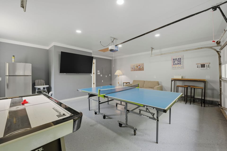 Game room with ping pong, air hockey, a TV, and lounge space for easy indoor fun.