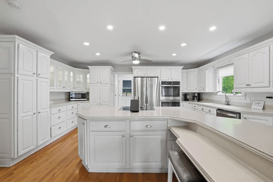 Spacious all-white kitchen with a large island, stainless appliances, and plenty of room for group meal prep.