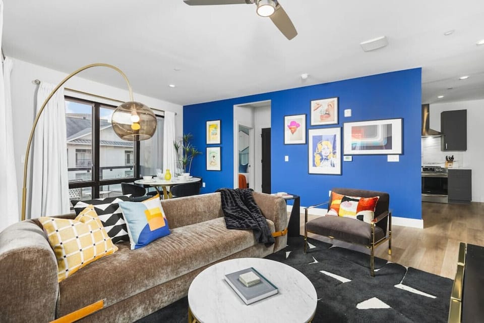 Spacious, colorful living room with a Smart TV, huge windows, wrap-around porch, and a dining table with seating for 4.