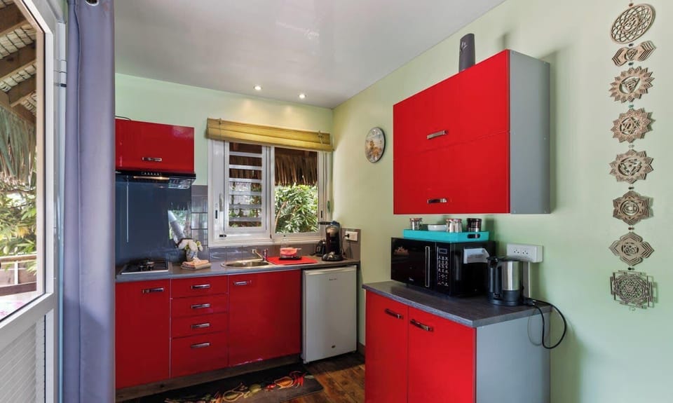 Bright kitchen with red cabinets, fully equipped and sunlit.