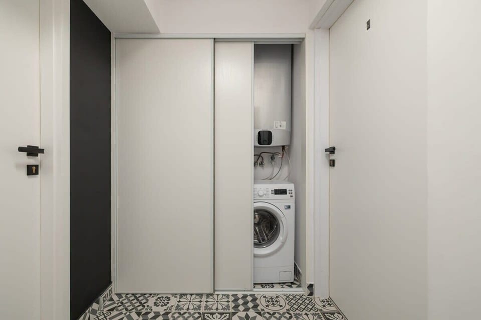 A small laundry area with a washing machine and white cabinetry in a compact space.