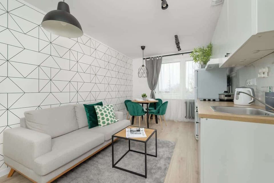 A stylish living room with a white geometric-patterned wall, a grey sofa, and a small table.