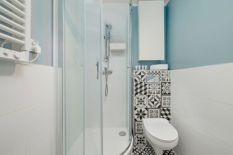A modern bathroom with a glass-enclosed shower, white fixtures, and patterned tiles.