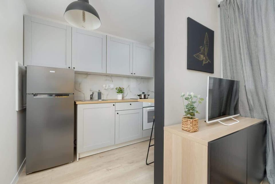A bright kitchen with white cabinets, a small dining table, and a large window letting in natural light.