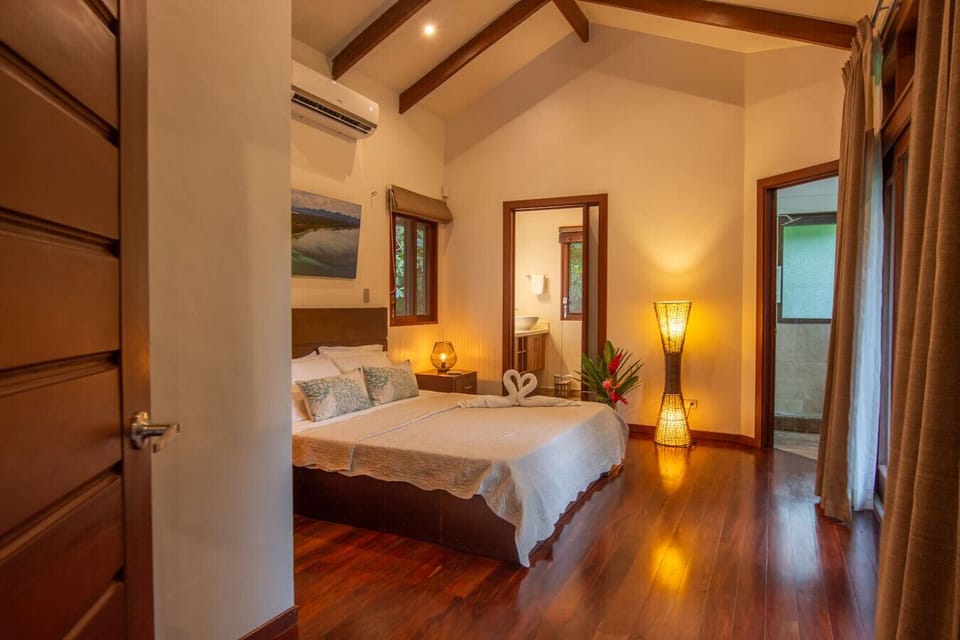 Spacious bedroom with queen bed, en-suite bathroom, and warm tropical lighting at Three Monkeys, Cahuita, Costa Rica.