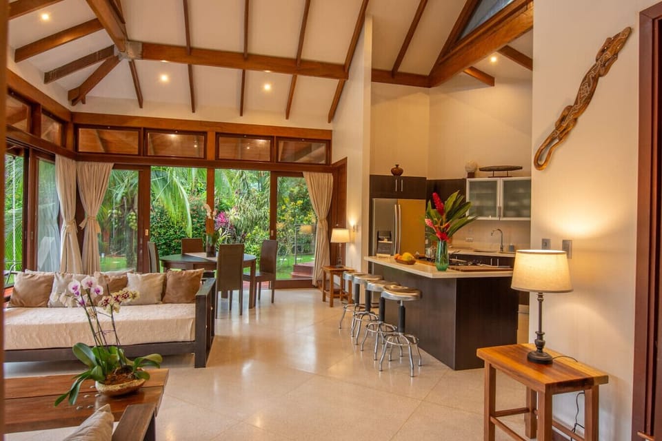 Open-plan living and kitchen area with high ceilings, natural light, and garden views at Three Monkeys, Cahuita, Costa Rica.