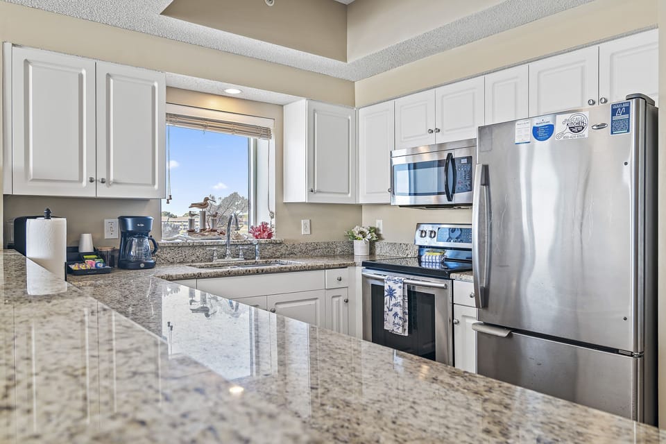 Kitchen has stainless appliances and granite countertops - fully stocked with more than the basics (coffee/tea bar, oils/spices, Tupperware, plenty of pots/pans/cookware)!