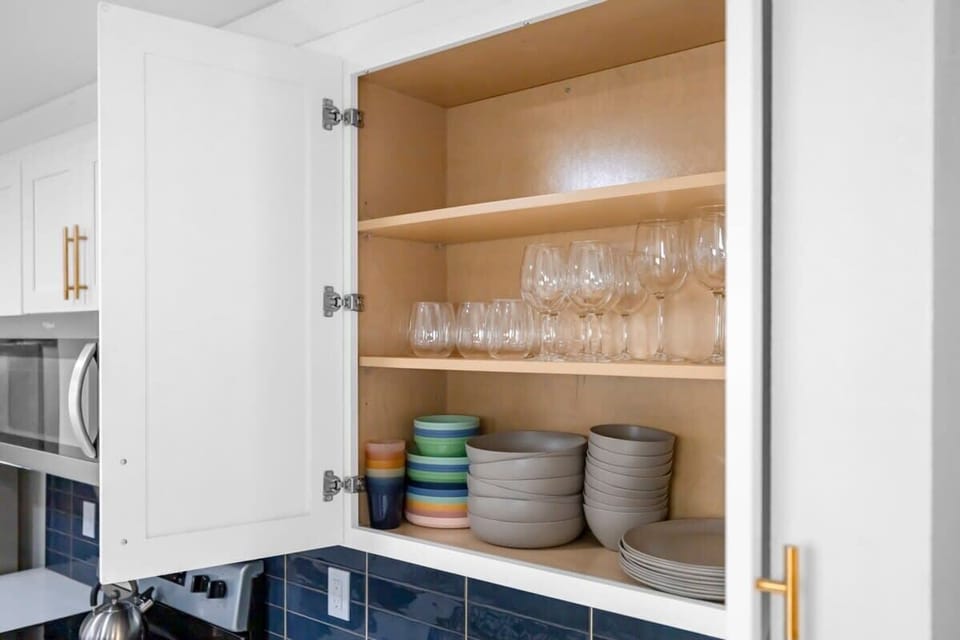 Open kitchen cabinet showing organized glassware and dishware with modern white cabinetry.