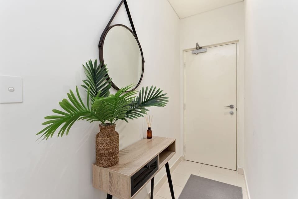 A fresh and welcoming entry, styled with greenery and a round mirror to set a pleasant tone as you walk in.
