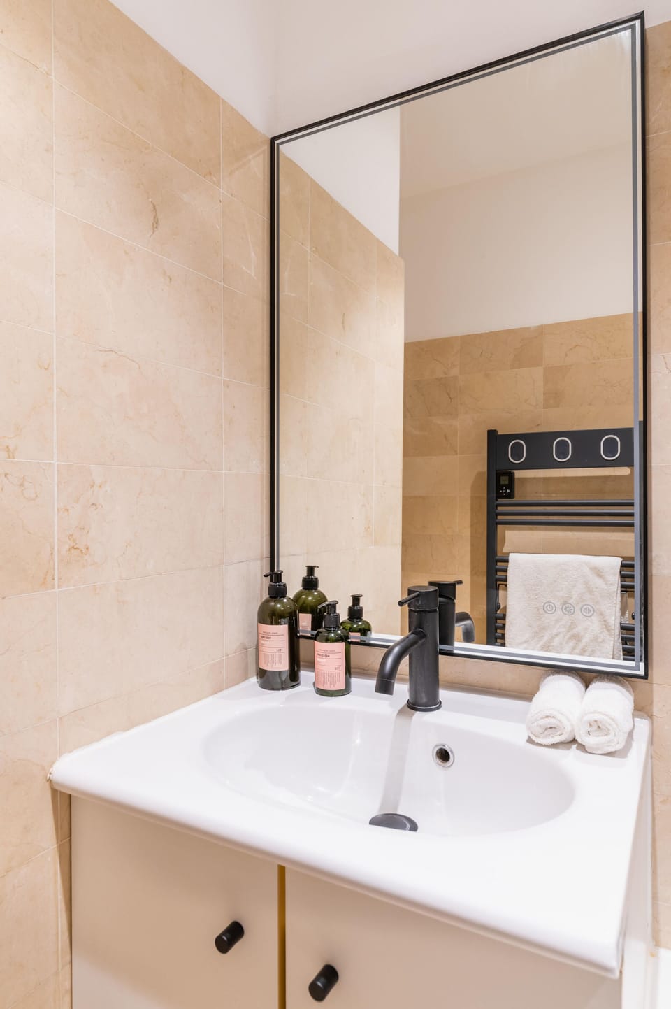 A backlit mirror, quality products, a scale, a hair dryer and a towel dryer.