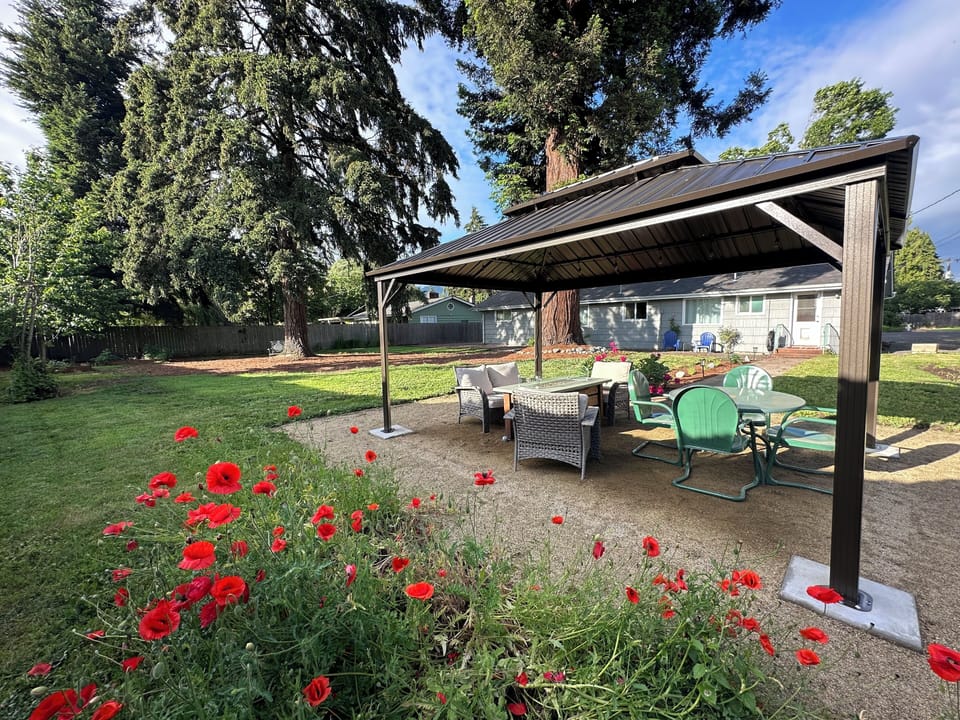 Large private backyard with outdoor seating, a fire table and lighted gazebo. 
