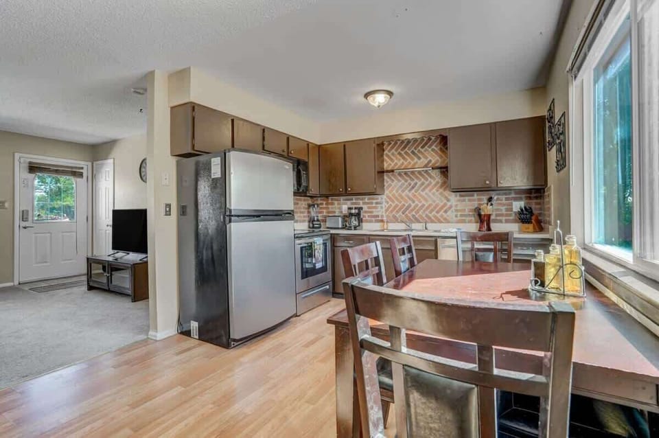 Bright kitchen with wood cabinets, a brick-style backsplash, and a dining table by the window—cook, plate, and linger over conversation in the morning light.