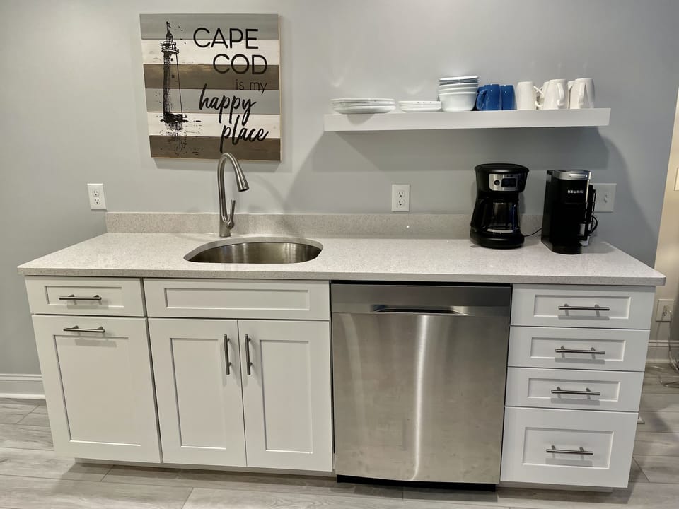 Two-part kitchen with coffee bar, sink, dishwasher,and two built-in trash bins. 