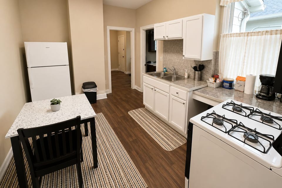Full galley kitchen with a gas range, granite-style counters, and a two-seat dining table