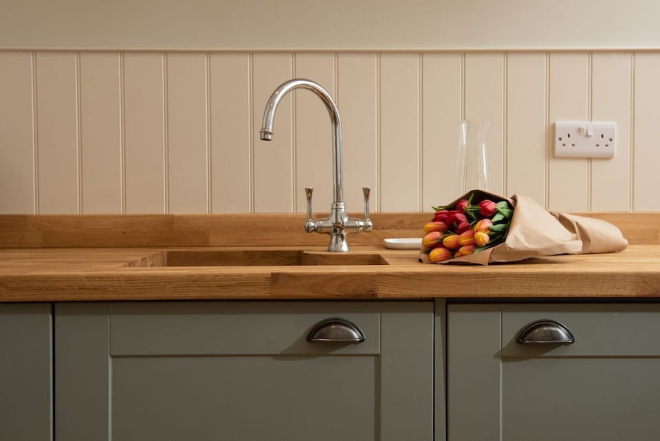 The Trouthouse - solid wood worktop and undermounted sink with characterful wall panelling above