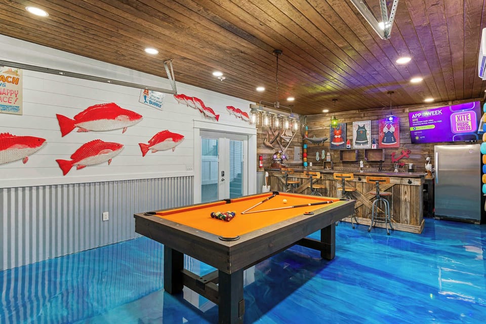 Spacious game room w/ pool table, vibrant lighting & playful wall art.