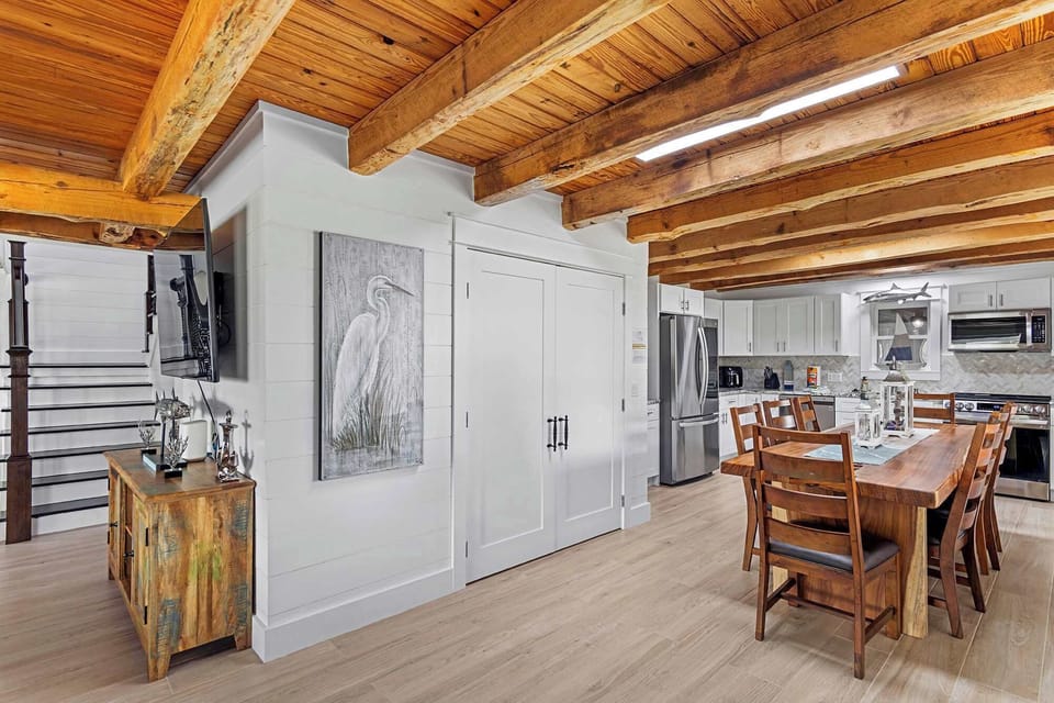 Dining nook w/ wood table set beneath warm, exposed ceiling beams.