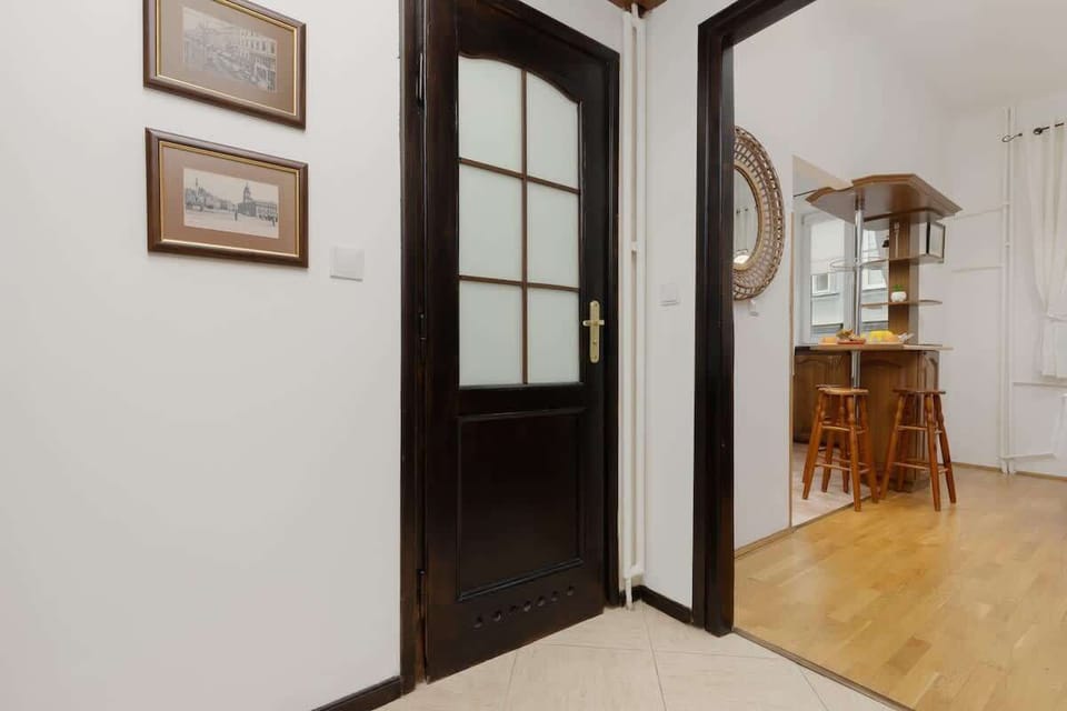A hallway leading to the dining area, showcasing elegant wooden doors with glass panels and framed wall art.
