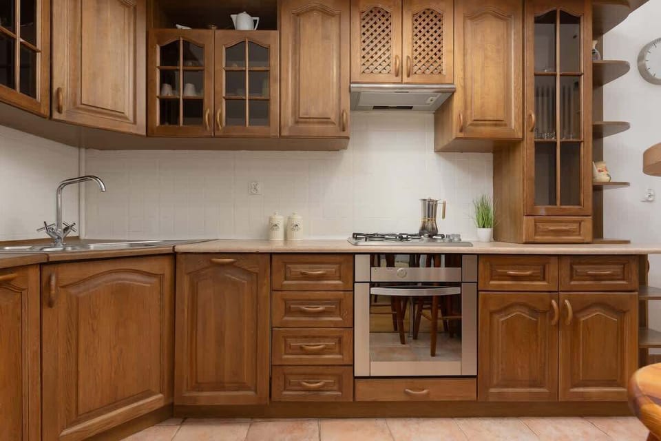 A traditional kitchen with wooden cabinetry, a stove, and tiled backsplash.

