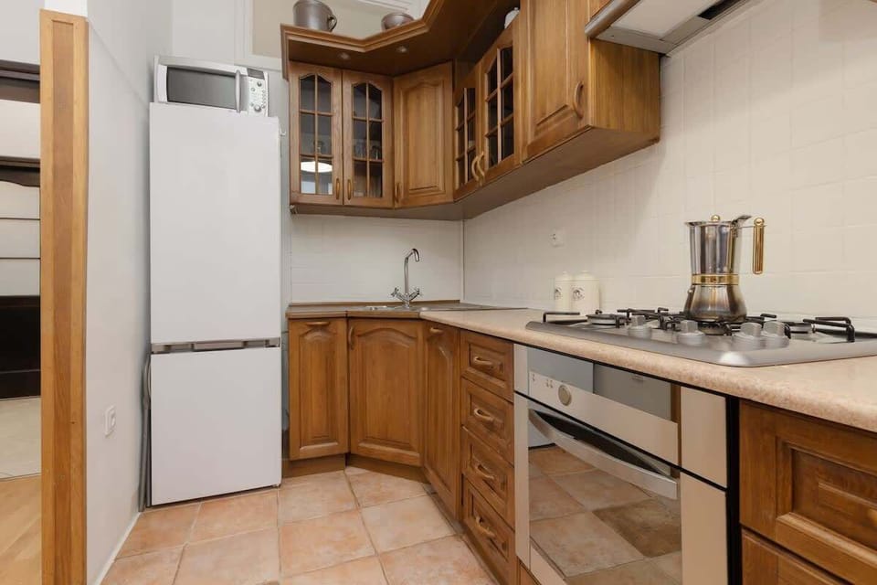 A traditional kitchen with wooden cabinets, a gas stove, and tiled flooring, creating a warm and rustic atmosphere.
