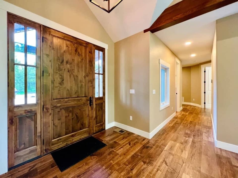 Front door and hallway leading to the powder room on the left, and the Primary bedroom on the right. Beyond that is the laundry area and the access to the stairs for the upstairs bedroom.