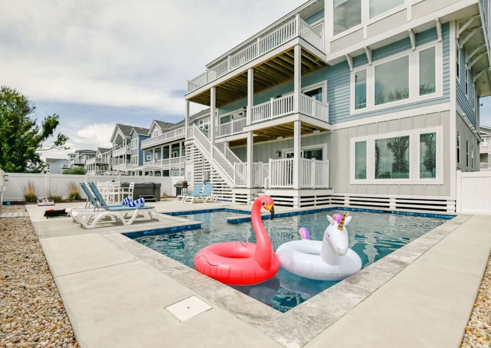 Sunlit pool deck w/ loungers & fun floats, perfect for cooling off after a beachy day.