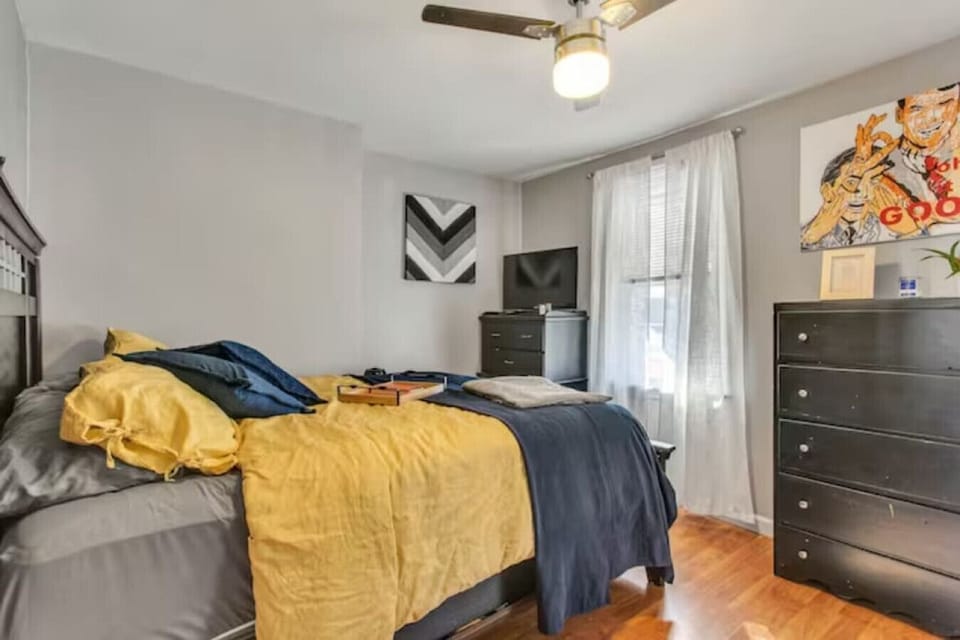 Unwind in the cozy bedroom featuring a queen bed with premium linens and ample storage space for your belongings. Large windows allow natural light to fill the room, creating a warm and inviting atmosphere.