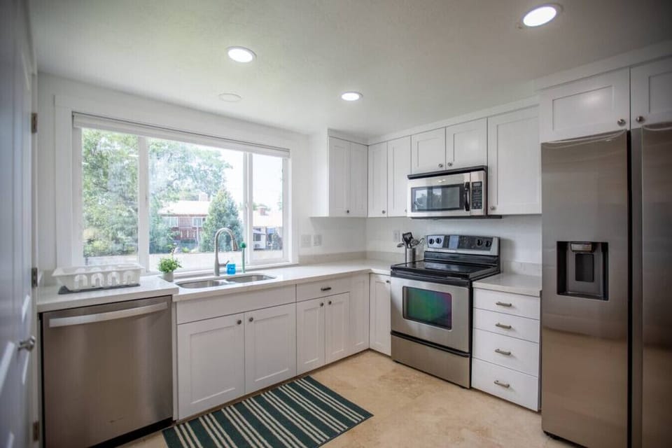 Open kitchen with natural light, stove, utensils, fridge, and oven.