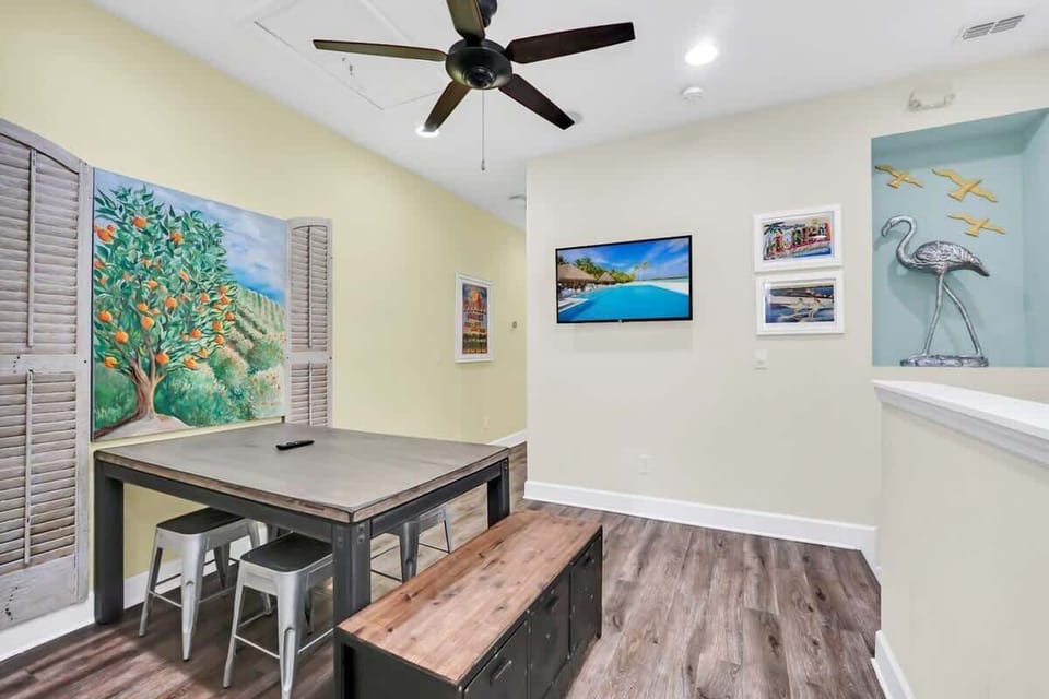 Dining area with a rustic table, metal stools, and coastal-themed wall art for a relaxed atmosphere.