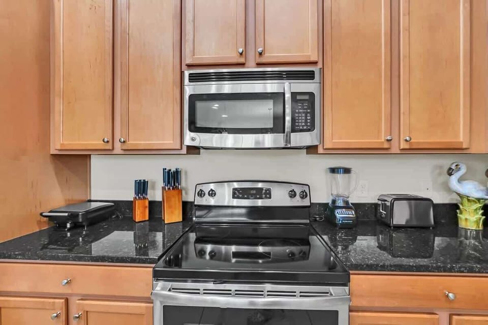 Modern kitchen with stainless steel appliances and black granite countertops.