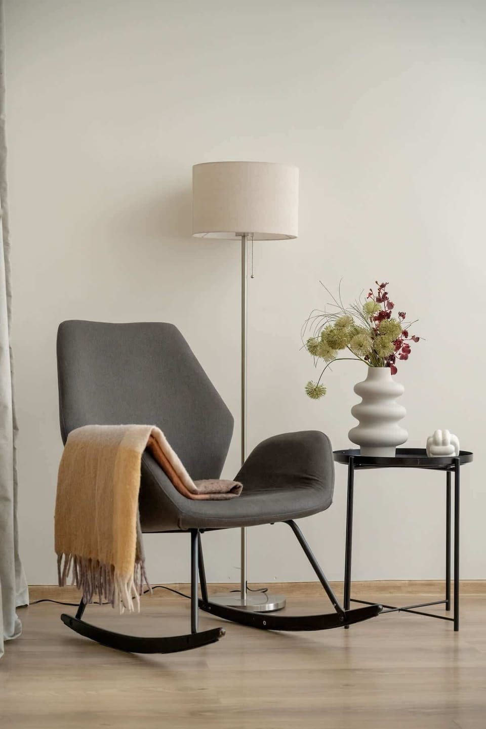 A small reading nook with a beige armchair, a side table, and a lamp.