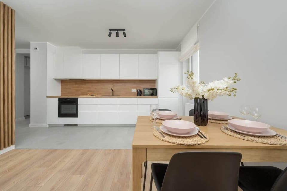 A fully equipped kitchen with white cabinetry and an orange backsplash, offering a sleek and modern design.