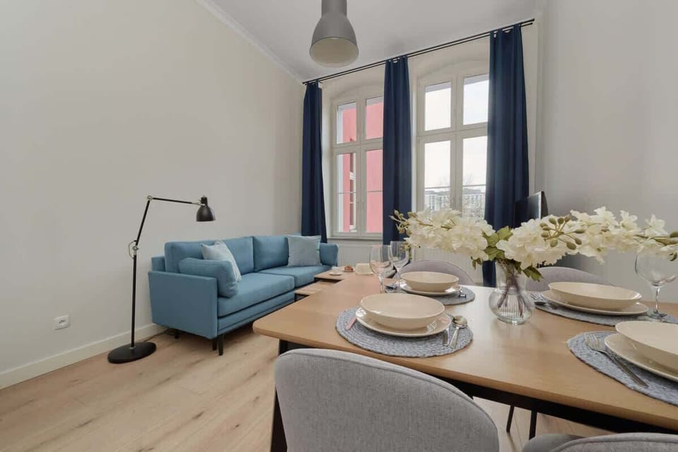 A bright and airy dining area connected to the living room, featuring a round dining table set with elegant tableware and fresh flowers.
