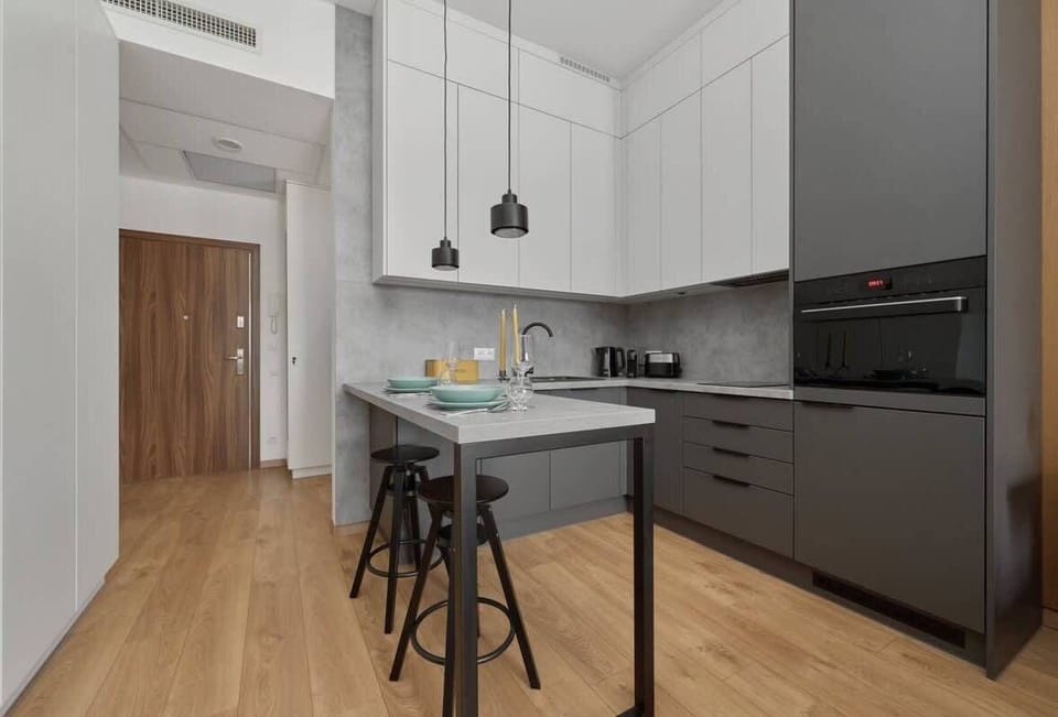 A contemporary kitchen with a sleek island counter, high stools, and minimalist design elements.
