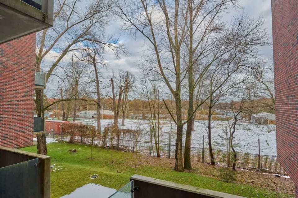 A scenic view of a serene river and lush trees, visible from the apartment's window, enhancing the tranquil ambiance.
