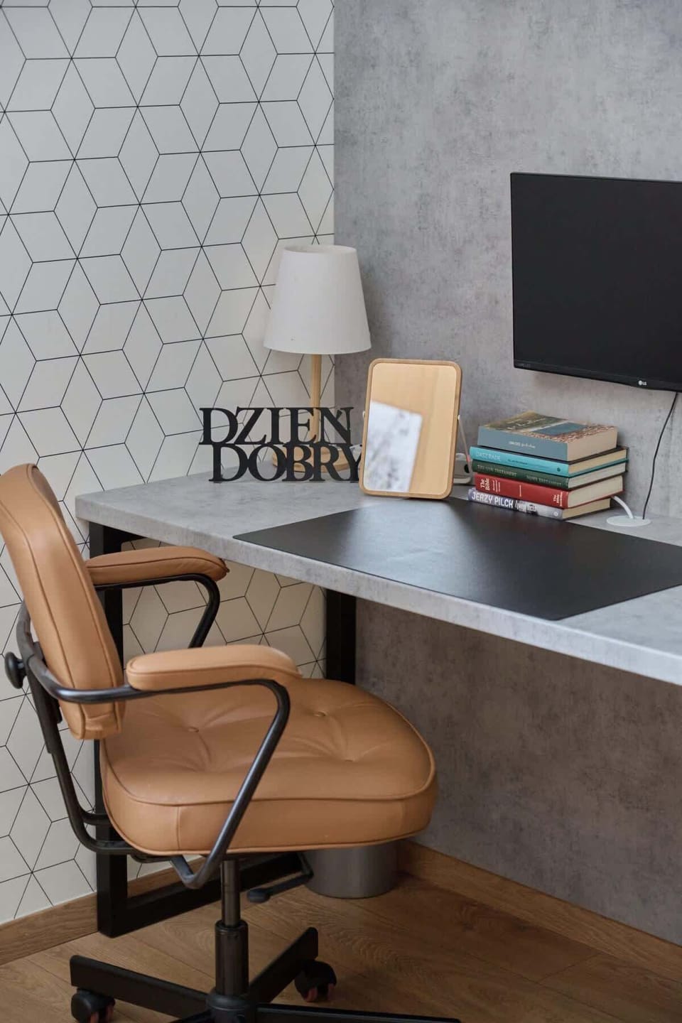 A well-organized workspace with a computer monitor, desk decor, and a leather office chair, ideal for remote work or study.
