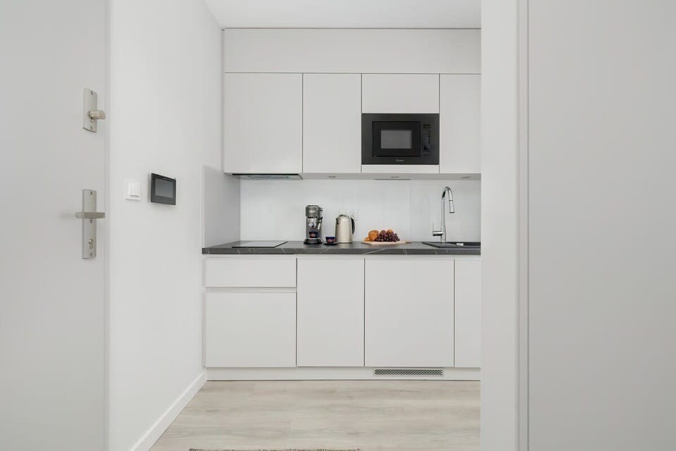 A minimalist white kitchen with integrated appliances, sleek cabinets, and a clean design, emphasizing a modern aesthetic.

